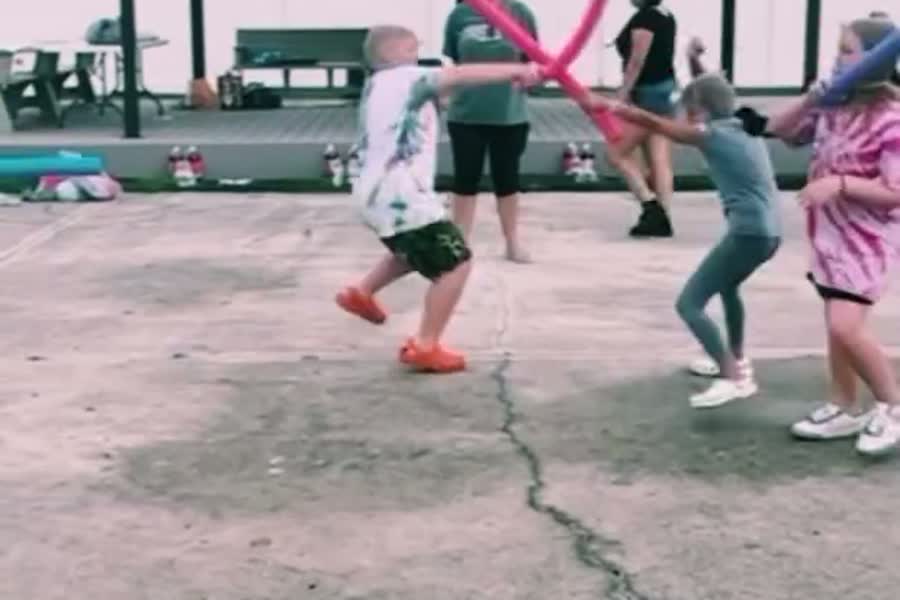Kids playing a pool-noodle game on the pavement at a Family Fun Night