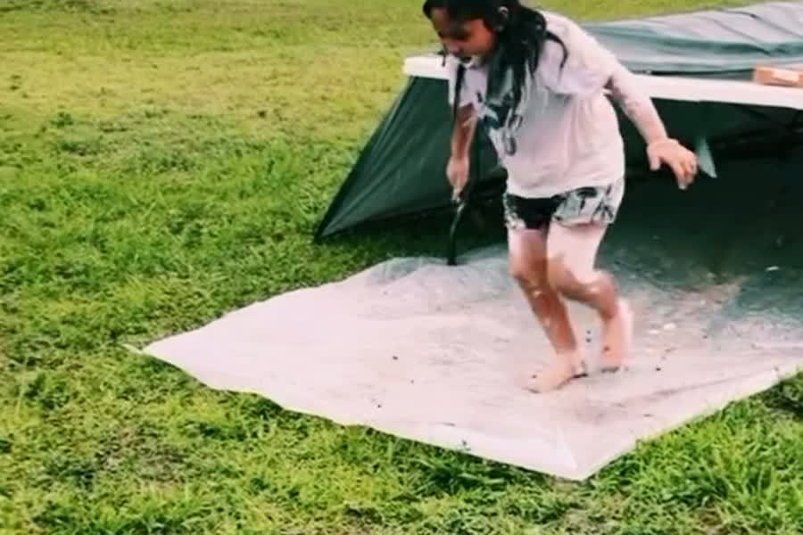 A child running off the end of a slip-and-slide on the church lawn