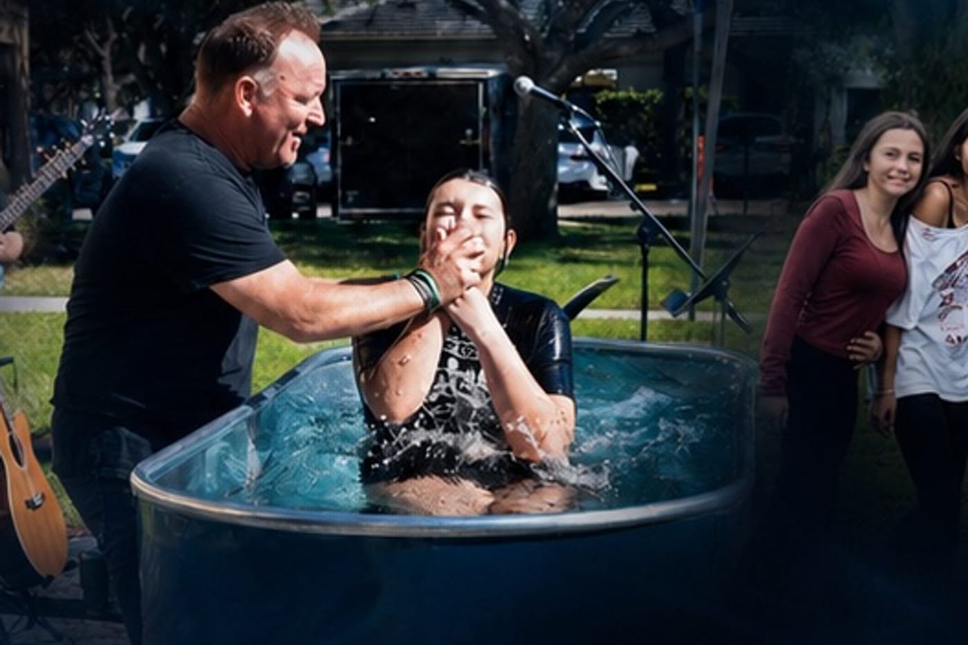 A student being baptized at New Life Church while friends cheer